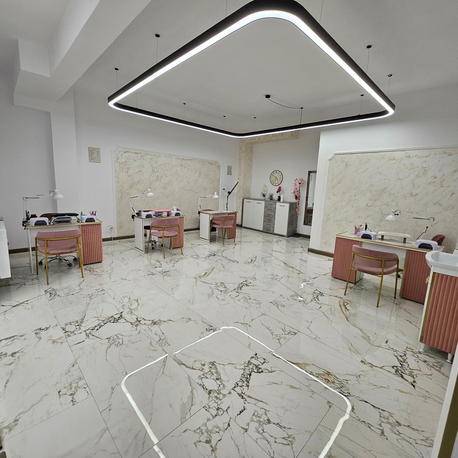 Sala de manichiură Pro Fashion, cu mese de lucru roz și aurii